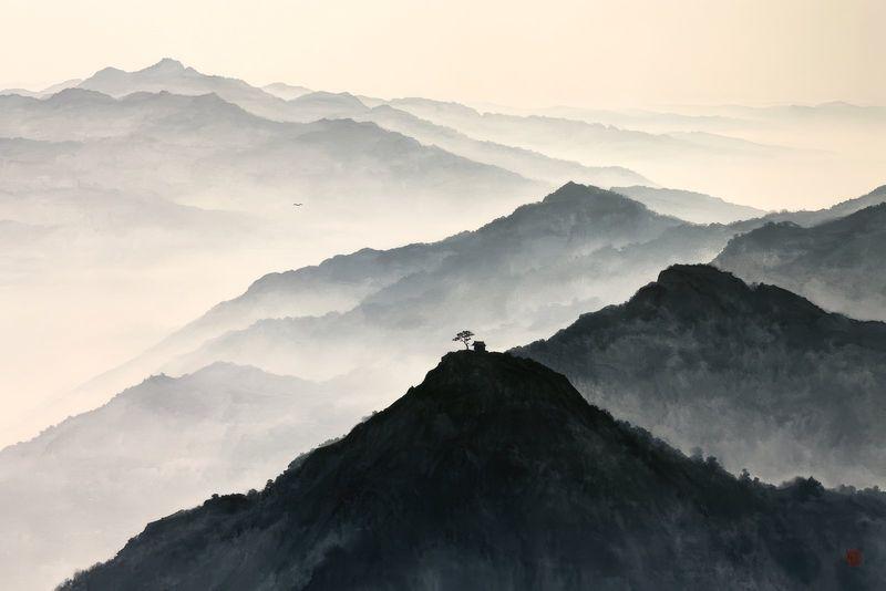 Layered mountain ridges in ink wash disappearing into mist